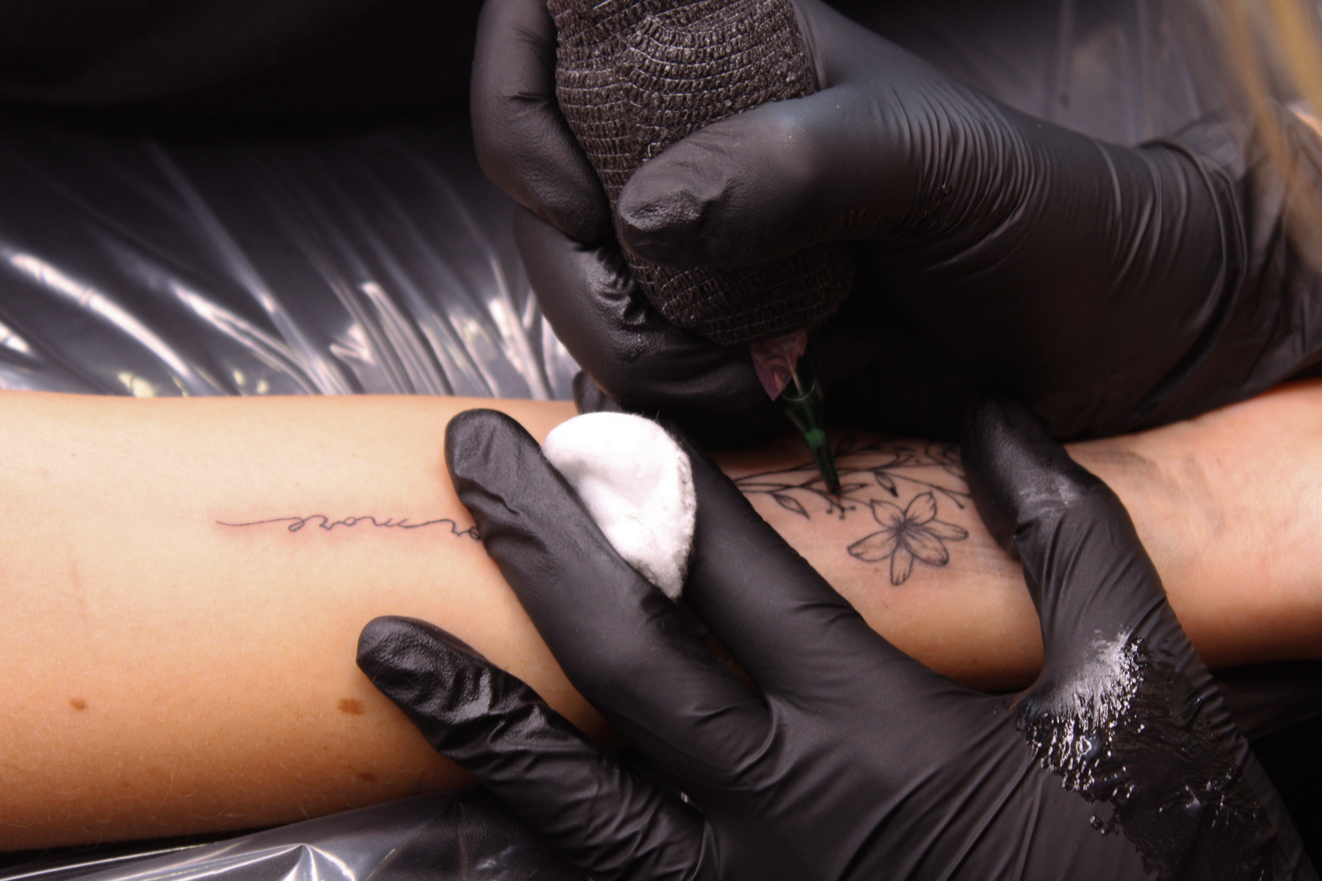Fine line floral tattoo in progress on a forearm