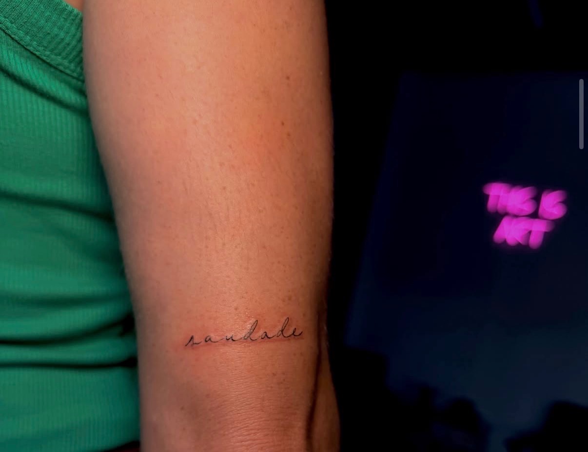 Delicate fine line script tattoo reading saudade